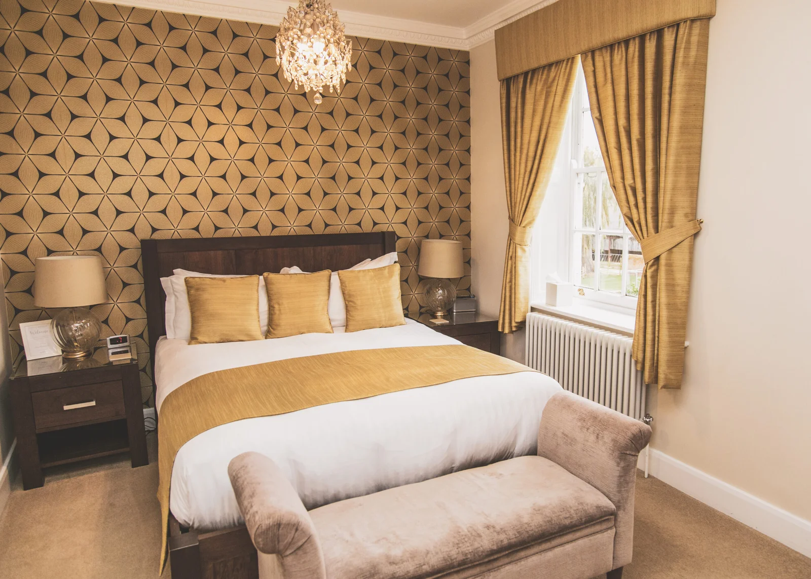 Luxury boutique guest bedroom Ramsay room at Downham Hall Essex with gold decor and chandelier