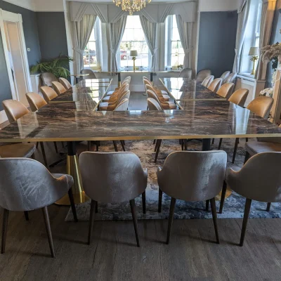 A U-shaped marble conference table with grey velvet chairs in the elegant De Beauvoir Suite for a board meeting.