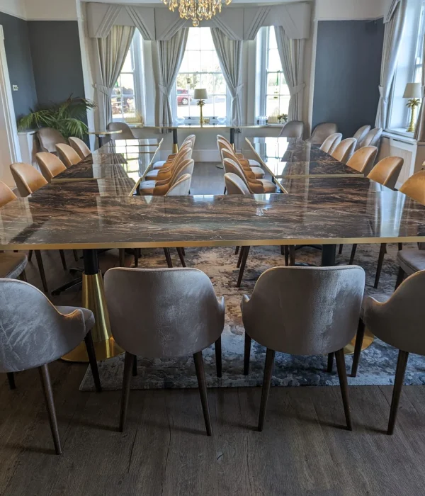 A U-shaped marble conference table with grey velvet chairs in the elegant De Beauvoir Suite for a board meeting.