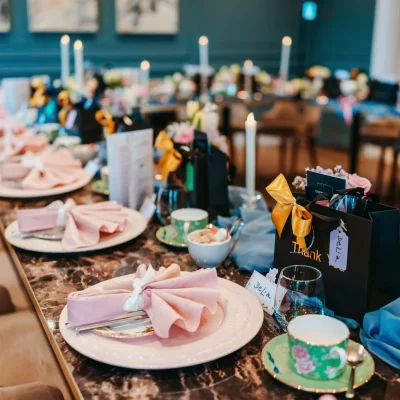 Elegant Table Setting in the De Beauvoir Suite Luxury dining table setup with marble tops, pink napkins, and personalized gift bags in the De Beauvoir Suite.