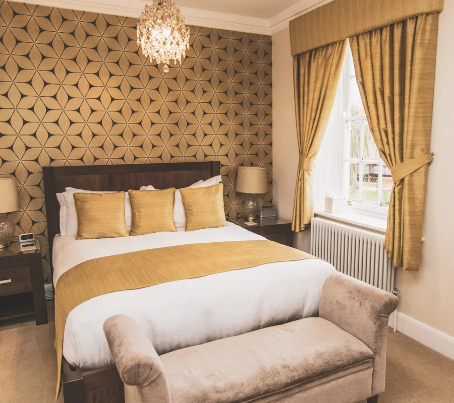 Elegant double bedroom with gold decor at Downham Hall wedding venue